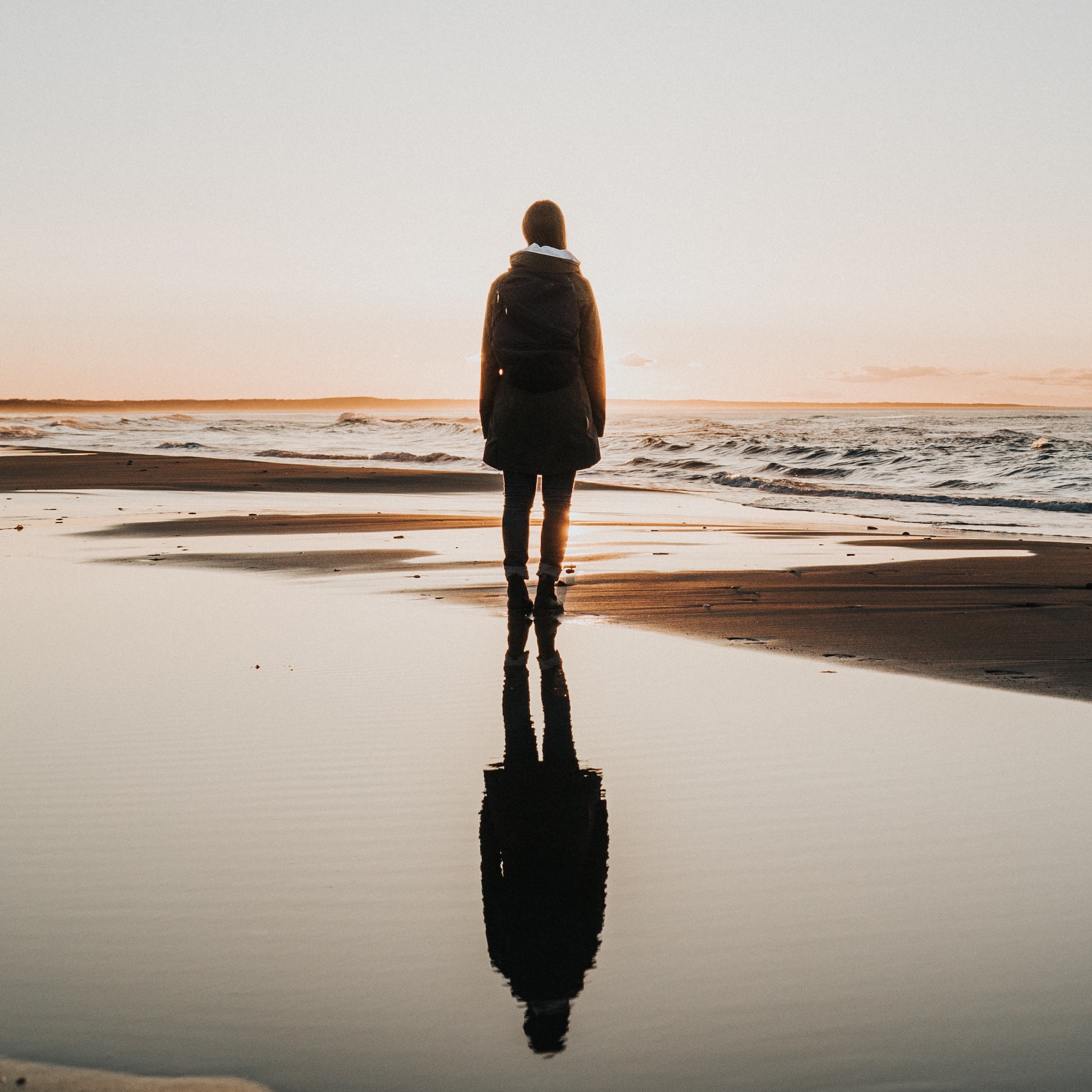 Femme sur une plage qui regarde vers l'océan